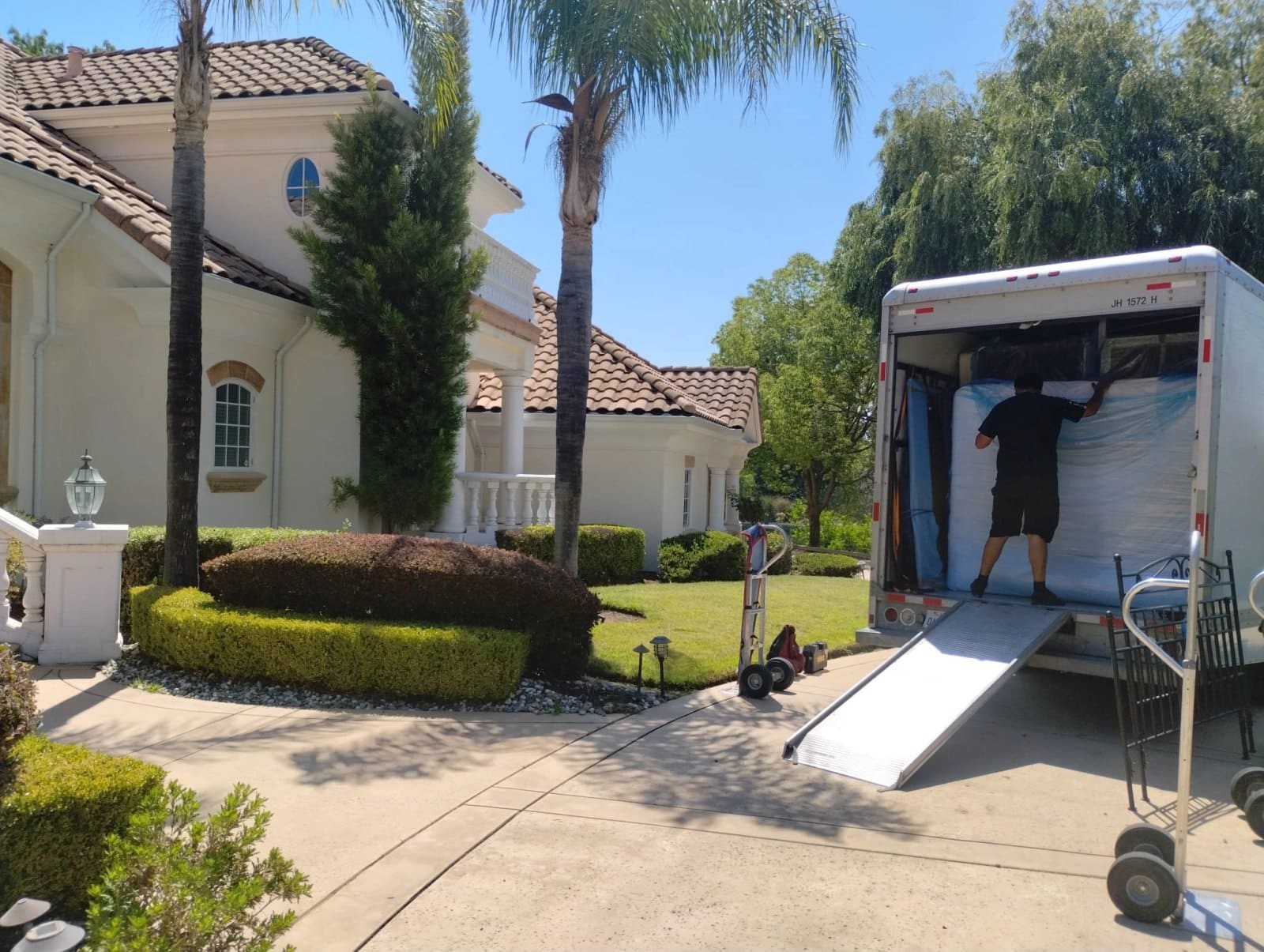 Moving truck with ramp backed up to residential home during daytime relocation service