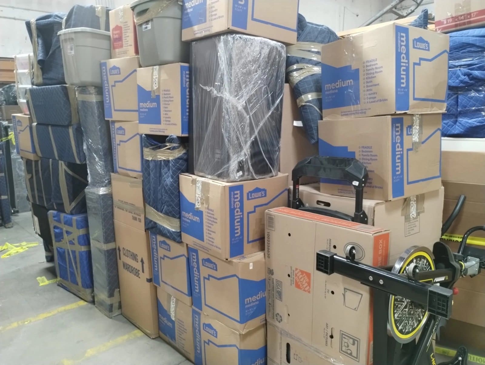 Stacked cardboard boxes labeled Lowes medium products in warehouse storage area with tools