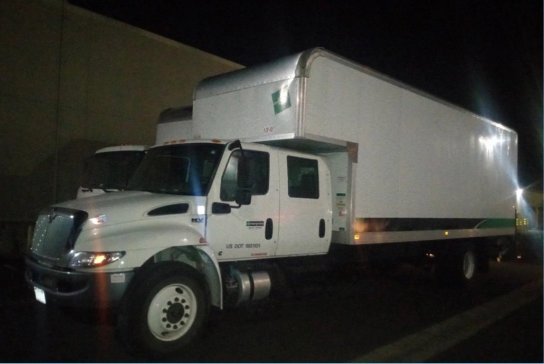 White commercial box truck parked at night with LED lights illuminating the cargo area