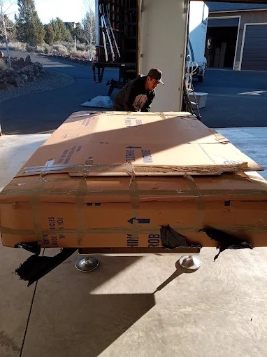 Workers loading large cardboard box onto delivery truck