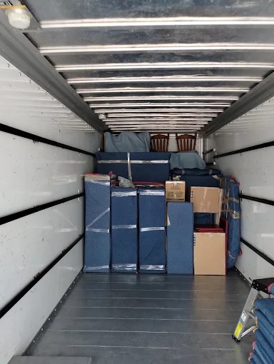 Interior of moving truck loaded with blue furniture boxes and cardboard moving containers
