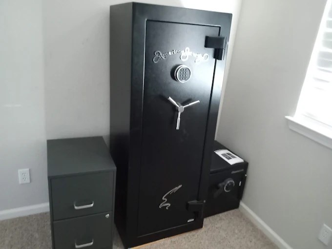 Black upright security safe next to filing cabinet in office corner