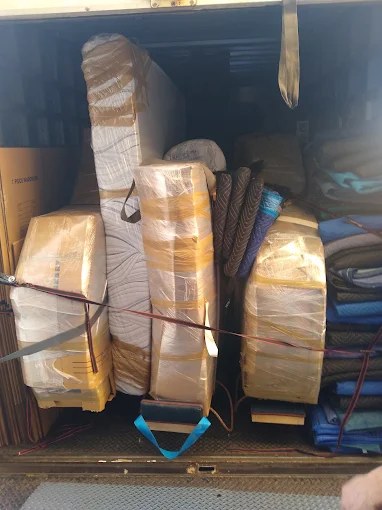 Packed moving truck loaded with wrapped furniture and rolled carpets secured with blue straps