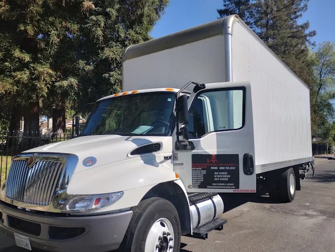 White International box truck parked on street with trees in background