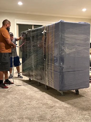 Man unwrapping plastic from large appliance in home interior