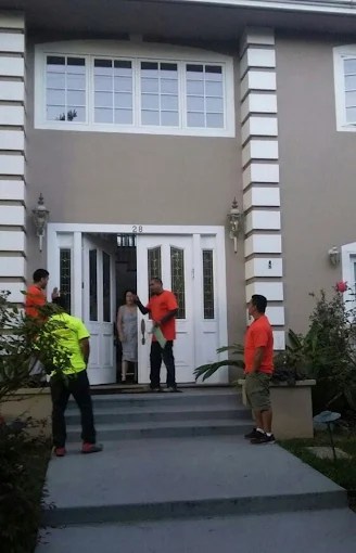 Team members in orange vests gathered at white entrance doors of gray residential building