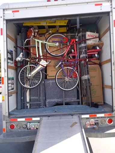 Moving truck cargo area packed with bicycles, cardboard boxes, and household items