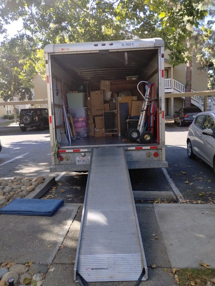 Moving truck with open cargo door and extended ramp on residential street